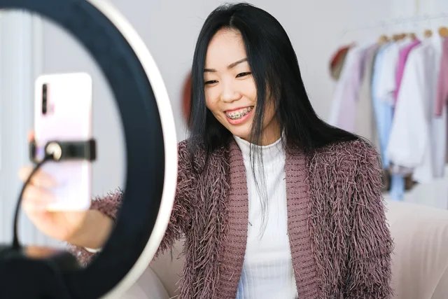 Smiling woman using smartphone and ring light for live streaming indoors. ASA influencer disclosure rules: what UK creators must label, with a ruling