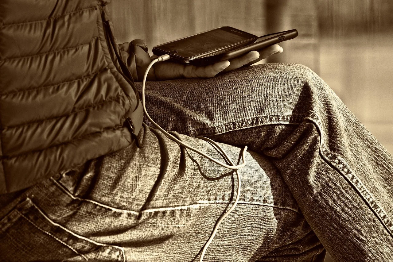 man, leg, hand, sitting, smartphone, wire, man holding smartphone, person, people, communication, technology, display, phone display, screen, brown technology, brown phone, brown mobile, brown community, brown communication, brown smartphone, brown telephone